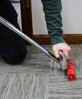 Person using Heavy Duty Seam Press Roller Extendable from 17 to 27 Inches on carpeted floor, showcasing handle and rollers.