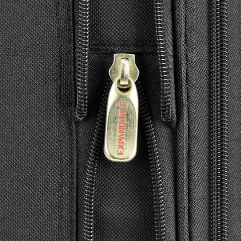 Luggage close-up: gold-tone expandable zipper pull on black fabric
