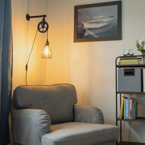 Industrial Pulley Wall Sconce Kit With Wire Cage Shade and Edison LED illuminating a living room with armchair and picture frame.