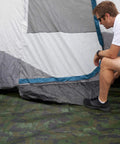 Rugged Camo Tarp 20ft By 30ft Heavy Duty Outdoor Shelter With 6 Oz Material spread under a tent, person inspecting the setup.