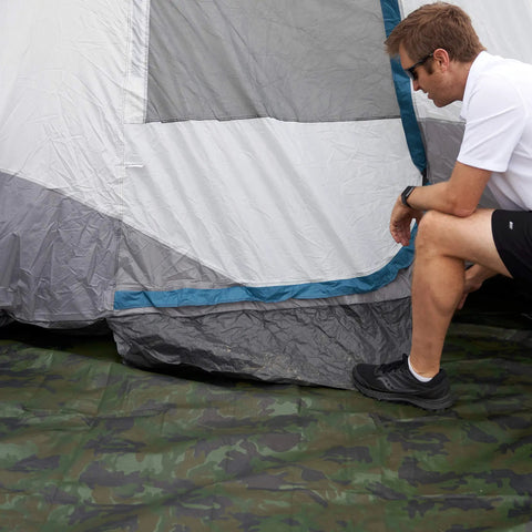 Rugged Camo Tarp 20ft By 30ft Heavy Duty Outdoor Shelter With 6 Oz Material spread under a tent, person inspecting the setup.