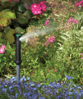Gear Drive Rotor Shrub Sprinkler With Adjustable Arc Range And 25 Foot Reach spraying water among colorful flowers in a garden.