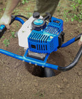 Gas Powered Post Hole Digger With 52cc 2.4 HP Two Stroke Engine drilling soil, showing blue handle and manganese steel auger bit