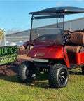 Red EZGO golf cart on grass near sign, showcasing modification options