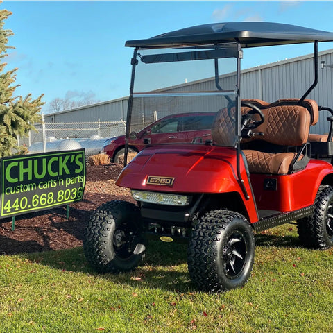 Red EZGO golf cart on grass near sign, showcasing modification options