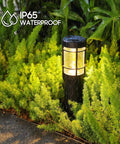 Close-up of IP65 waterproof solar pathway light in rain, surrounded by greenery, part of Solar Pathway Lights Pack Of 6 with Warm White and Color Changing Modes outdoor setup.
