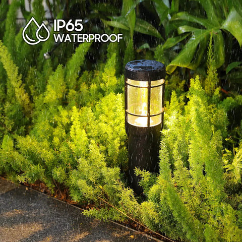 Close-up of IP65 waterproof solar pathway light in rain, surrounded by greenery, part of Solar Pathway Lights Pack Of 6 with Warm White and Color Changing Modes outdoor setup.