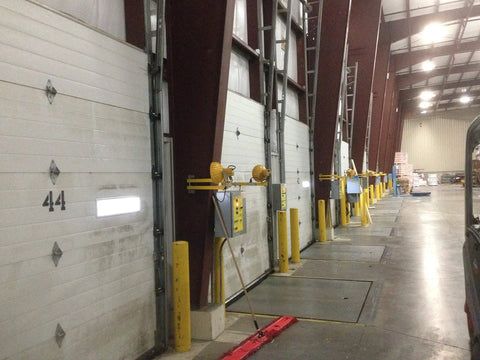 Warehouse loading dock with multiple garage doors featuring Energy Saving Garage Door Seal Hinge for 4 Panel Doors 12 Foot Wide and Over With Auto Self Adjusting Spring Loaded Gap Seal That Blocks Dirt Dust and Moisture and Ensures Tight Closing Easy Install Mfg C4416 40