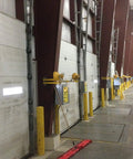Industrial loading dock with multiple white sectional garage doors and yellow bollards, suitable for Energy Saving Garage Door Hinge For 12 Foot Wide And Over 5 Panel Doors With Self Adjusting Seal System Reducing Dirt Dust Rain And Moisture, Spring Loaded For Tight Closings Up To One Quarter Inch Gap, Easy Install.