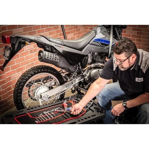 Mechanic using Go-To Motorcycle Tool Kit with Roll Pouch for roadside and travel repairs, featuring wrenches and sockets.