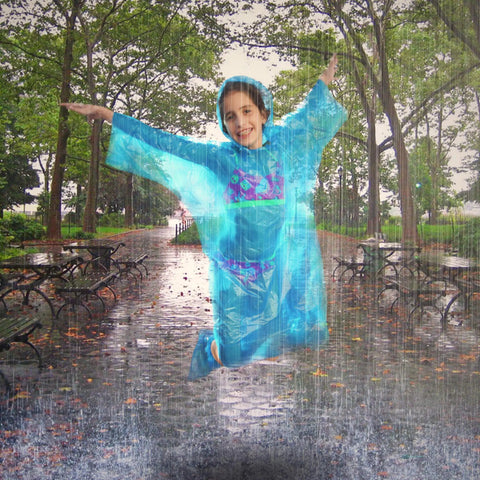 Child jumping in blue poncho in park, Extra Thick Rain Ponchos Family Pack With Shoe Covers Included 10 Pack For Rainy Days And Outdoor Adventures