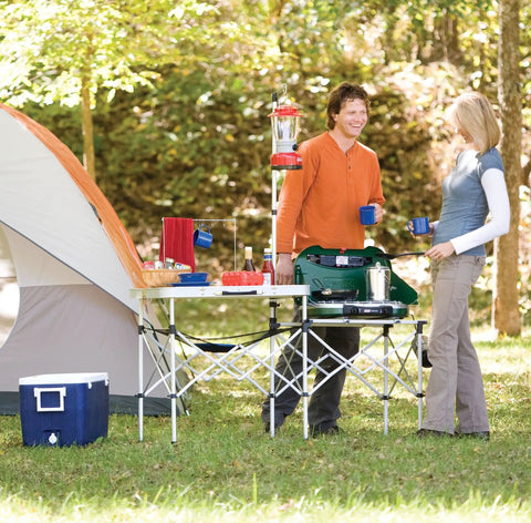 Portable Go To Camp Kitchen With Large Food Prep Area Folding Outdoor Kitchen For Camping Tailgating And Grilling Includes Side Table Utensil Hooks And Mesh Storage set up by tent with people using it