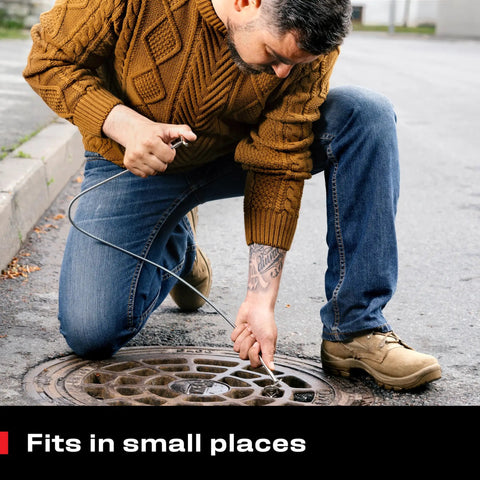 Person using multipurpose pickup tool set with 36 inch flexible claw grabber for DIY home auto and garage use in a sewer grate.