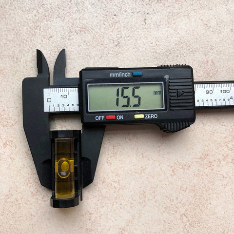 Front view of a digital caliper-style gunsmith level with yellow bubble vial and magnetic base, reading 15.5 mm