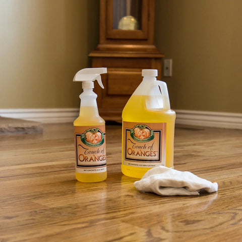 Orange Oil Wood Cleaner And Polish Spray For All Wood Surfaces Restorer And Conditioner, shown in gallon and spray bottle on floor