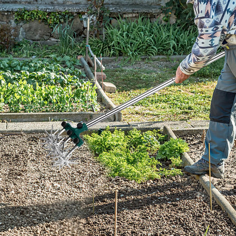 Person using Rotary Cultivator Garden Tiller with adjustable stainless steel handle and aluminum tines in vegetable garden.