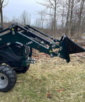 Compact tractor with Beefy Mini Wrecker Stump Bucket for small tractors, front-end loader attachment in yard clearing setup.