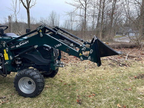 Compact tractor with Beefy Mini Wrecker Stump Bucket for small tractors, front-end loader attachment in yard clearing setup.