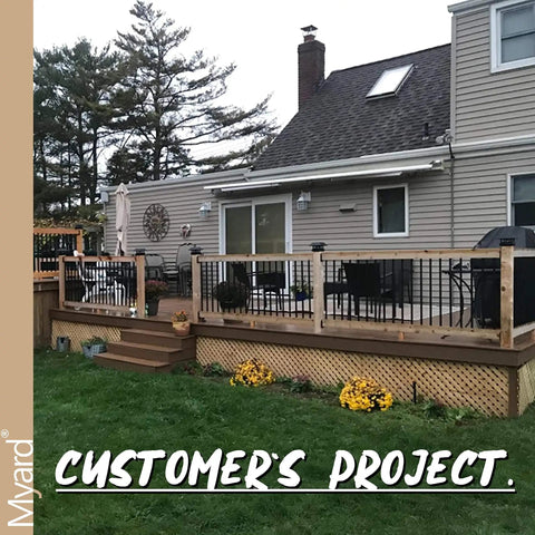 26 Inch Hollow Round Iron Deck Balusters Matte Black in a customer's outdoor railing project with wooden deck and plants.