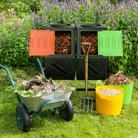 Dual Chamber Tumbling Composter With Sliding Door Heavy Duty Plastic Compost Bin For Backyard Waste Turn Trash Into Treasure With Two Eighteen And A Half Gallon Bins, shown in a backyard with open doors and garden tools.