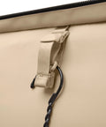 Beige softside luggage exterior with beige nylon strap, plastic buckle, and black carabiner clip