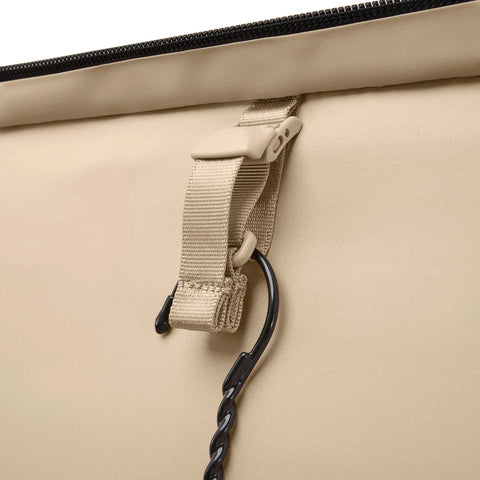 Beige softside luggage exterior with beige nylon strap, plastic buckle, and black carabiner clip