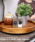 Slick 13 Inch Acacia Wood Lazy Susan Turntable Organizer For Kitchen Cabinets displaying spices and greenery on a smooth circular tray.
