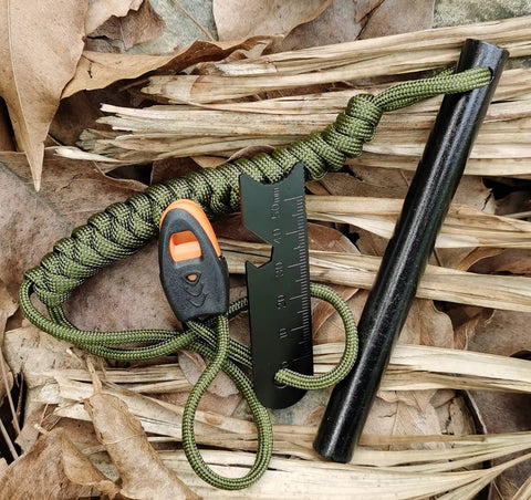 5 Inch Weatherproof Flint Ferro Rod Fire Starter Kit with whistle, paracord lanyard, and steel multitool striker on leaves