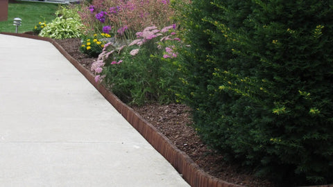Brown Lawn And Landscape Border Edging For Garden Beds And Walkways With Flexible Design lining a flower bed along a sidewalk.