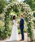 Couple under Sturdy Garden Pergola Arbor Arch Trellis With 55 Inches Wide And 94.5 Inches Tall Built To Last, flower-adorned.