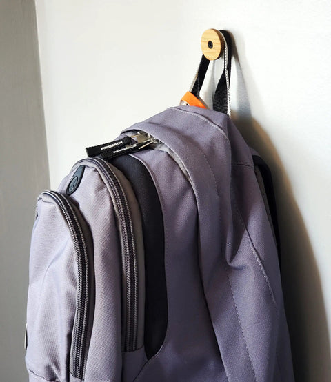 Compact backpack hanging on a bamboo hook against a wall, demonstrating space-saving storage solutions.