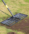 Heavy Duty Lawn Leveling Rake with stainless steel handle on grass, showing soil smoothing in progress. 72 inch yard tool for lawns.