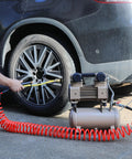 1/4 In X 30 Ft Polyurethane Recoil Air Hose With Bend Restrictors in use, connecting air tool to vehicle tire, red coiled hose visible