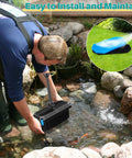 Person installing All In One Pond Filtration System With 660GPH Fountain Pump Kit in outdoor koi pond, showing ease of setup.