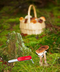 Kids Pocket Knife Toy 4.4 Inch VX Red Swiss Army Style Pretend Tool placed on mossy forest ground with mushrooms and basket