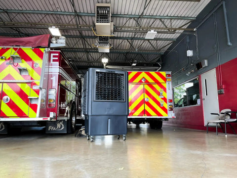 Industrial Swamp Cooler With 22000 CFM And 46 Gallon Water Tank delivers serious chill in a fire station garage with trucks.