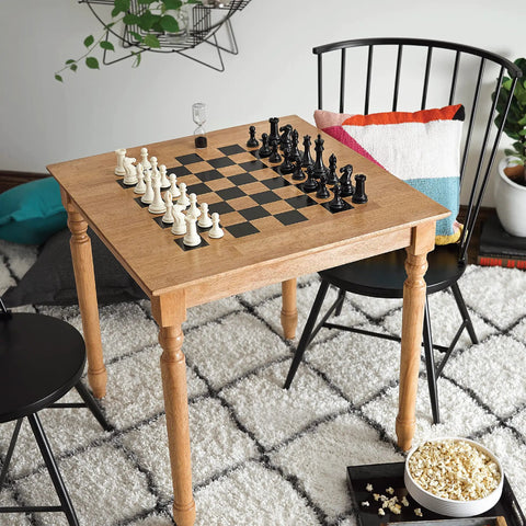 Wood table with chess setup beside chairs in cozy room, popcorn bowl on floor, emphasizing home leisure.