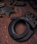 Heavy Duty Double Lock Hinged Handcuffs With Two Keys And Case Real Steel Pro Grade Security Cuffs In Black on wooden surface