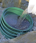 Water being poured over the 9-Piece Patented Stackable Gold Prospecting Sifting Pan Set With Stainless Steel Mesh on rocks.