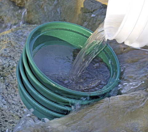 Water being poured over the 9-Piece Patented Stackable Gold Prospecting Sifting Pan Set With Stainless Steel Mesh on rocks.