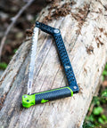 Folding Camp Saw With 12 Inch Blade For Backpacking, Hiking, Camping And Bushcraft, bright green accents on log