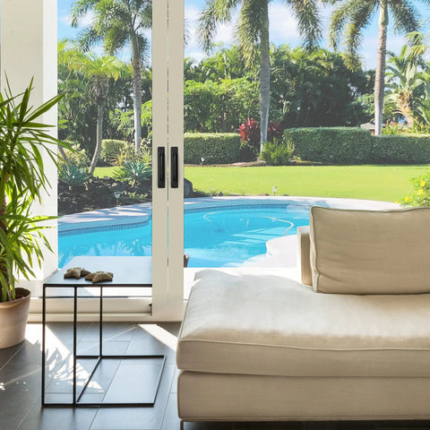 Modern living room with glass doors leading to a pool and garden view