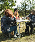 Group camping with Apex Fold-Up Stool G-140 around outdoor table, tent, and hammock in background