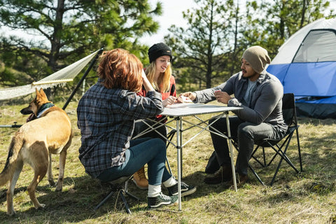 Group camping with Apex Fold-Up Stool G-140 around outdoor table, tent, and hammock in background