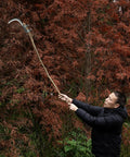 Man using All-Purpose Garden Sickle With Replaceable Wooden Handle And Heavy-Duty Manganese Steel Blade For Weeding, Mowing, And Yard Cleanup