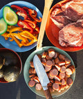 Colorful camping food preparation on plates next to Solo Camp Table Set For One 6 Piece Plastic BPA Free Mess Kit on a table.