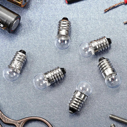 20 Pack Real Deal E10 Miniature Screw Light Bulbs 2.5V 0.3A Tiny Replacement Warm Glow for Toy Cars and Circuit Models Rock Solid E10 Socket Mini Bulb Haul on a grey surface with batteries and tools.