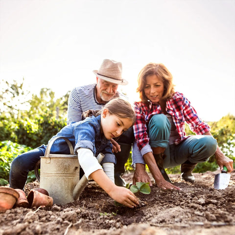 Family planting in a garden with watering can and pots