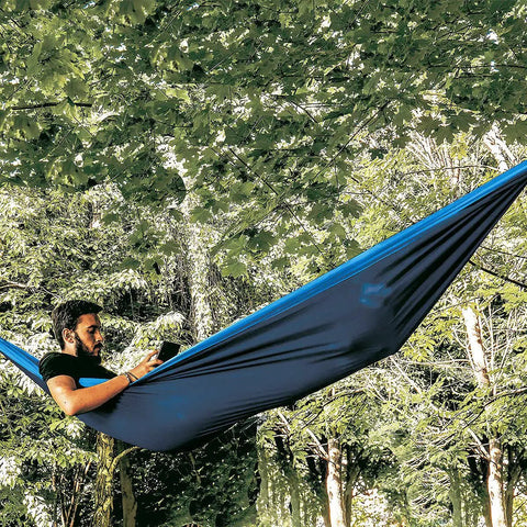Person lounging in Double Travel Hammock Ultralight Parachute Nylon With Breathable Fabric in forest setting