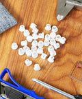 30 Pack 8mm White Plastic Hole Plugs With Snap In Locking End Caps for furniture, visible on a wooden table with tools.